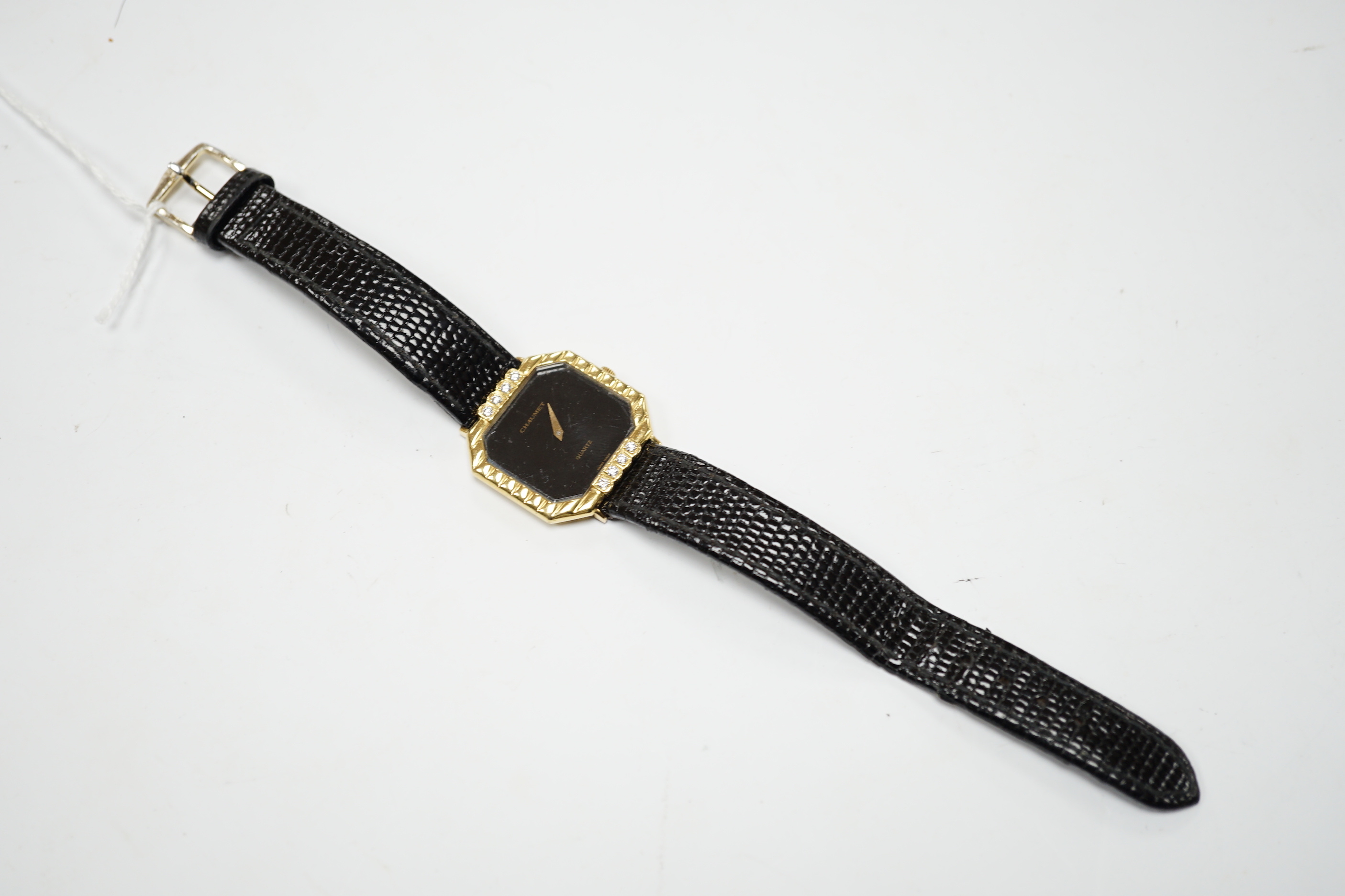 A lady's 18ct gold Chaumet quartz black dial dress wrist watch, with eight stone diamond set bezel, on an associated leather strap.